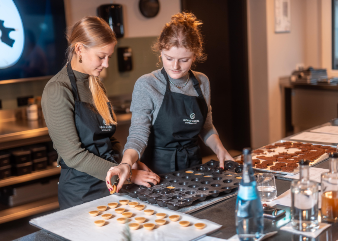 Zwei Workshopteilnehmerinnen legen fertig gebackene Törtchenböden auf den Tisch.